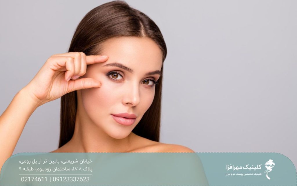 دختری که صورت خود را به یک طرف چرخانده و با انگشت چشم و ابروی خود را نشان می دهد