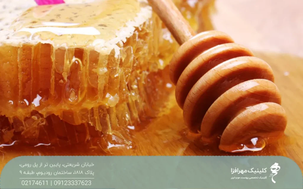 یک تکه موم عسل که در کنار آن یک قاشق چوبی عسل وجود دارد