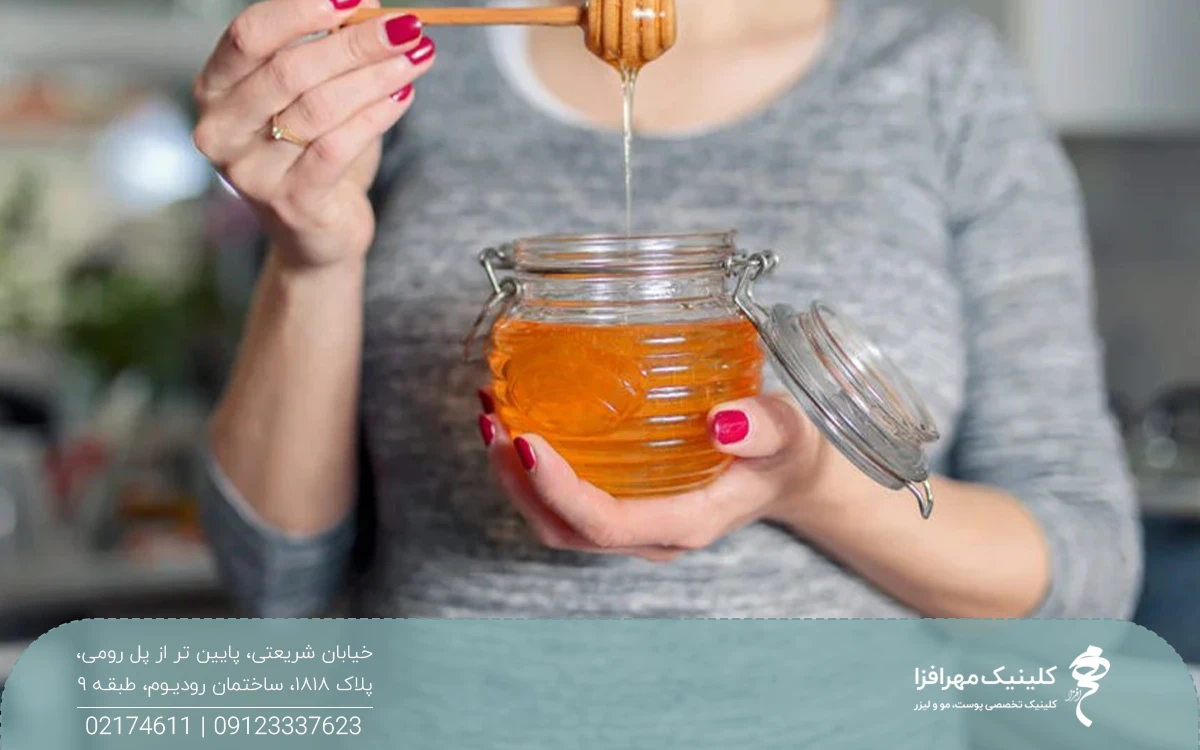 خانمی که یک ظرف پر از عسل را در دست دارد و یک قاشق چوبی را از داخل عسل بیرون کشیده است